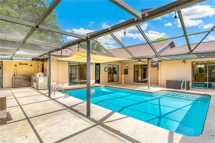 Screened-in swimming pool with integrated steps, surrounded by a textured concrete patio