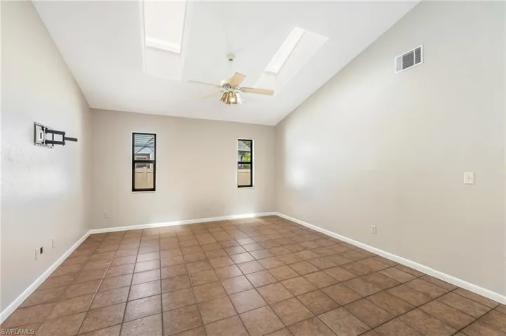 Vaulted ceiling featuring skylights and a ceiling fan