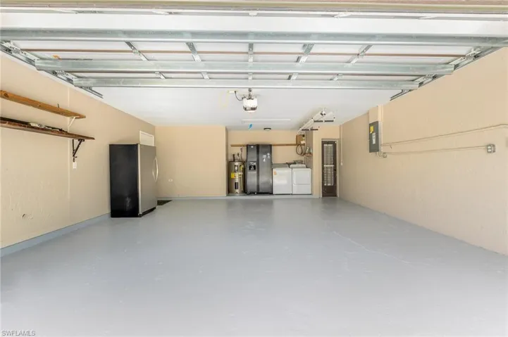 Spacious garage featuring newly painted light gray floor coating and cream-colored walls, and overhead lighting.
