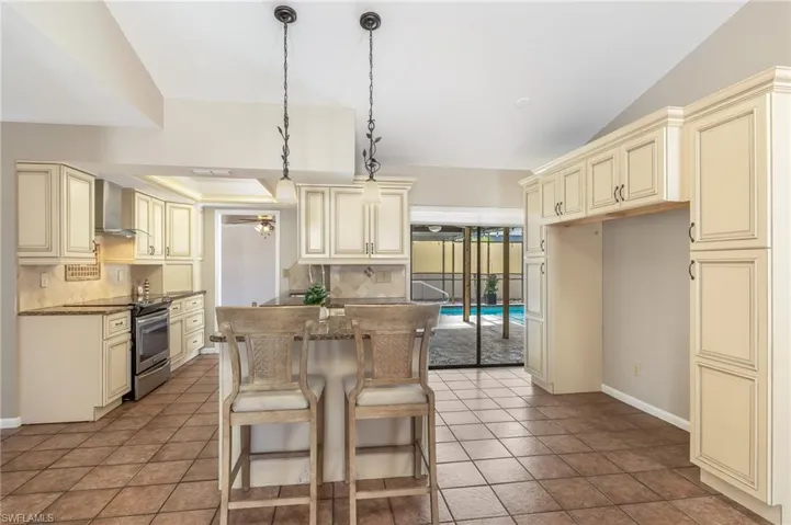 Expanded Kitchen with breakfast bar island, granite, almond colored cabinetry, pendant lights.