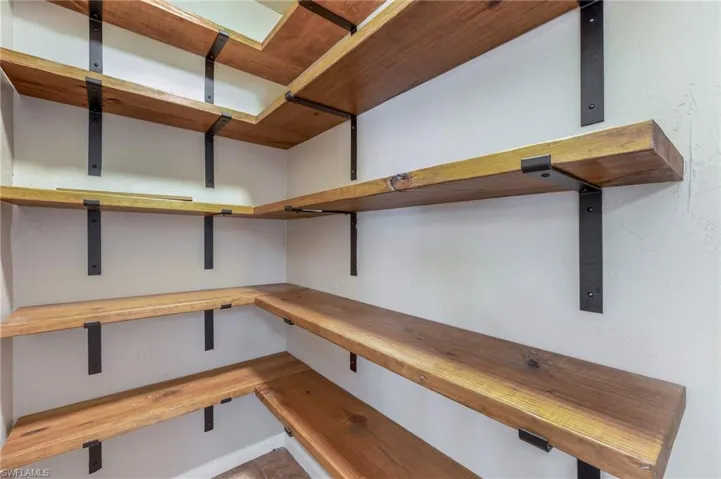 Walk-in pantry with wooden shelving.