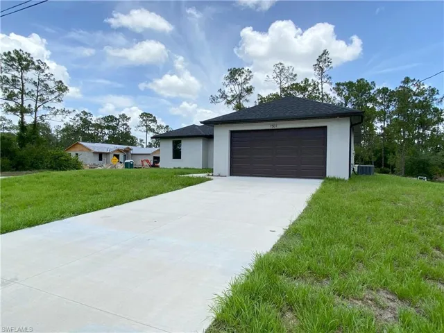 View of front of home featuring concrete driveway, a front yard, stucco siding, an attached garage, and roof with shingles