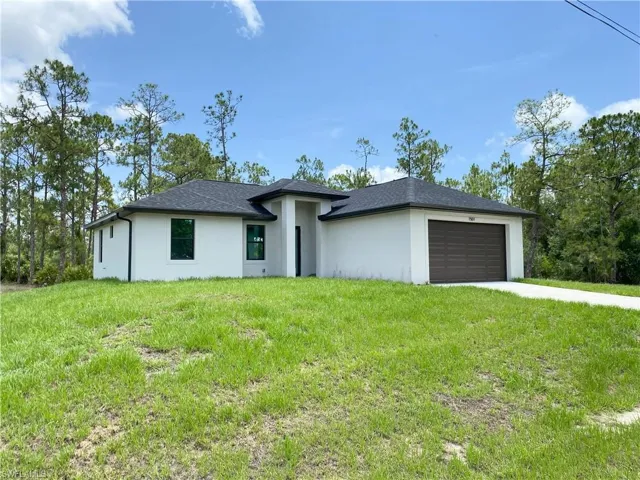 Prairie-style house featuring stucco siding, an attached garage, concrete driveway, and a front yard