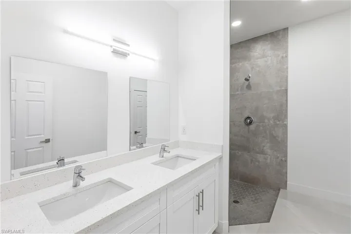 Bathroom with tile patterned flooring, vanity, and tiled shower