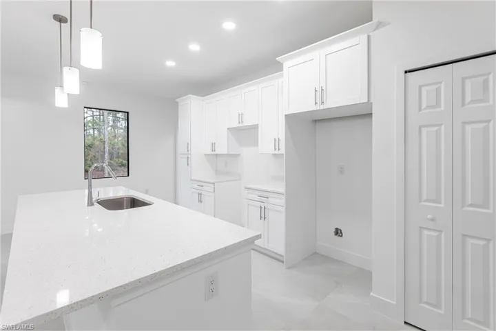 Kitchen with decorative light fixtures, sink, a center island with sink, and white cabinets