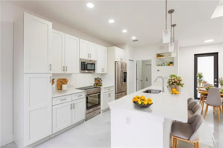 Kitchen featuring appliances with stainless steel finishes, sink, and white cabinets