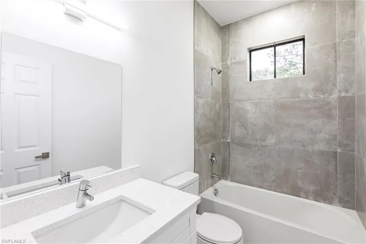 Full bathroom featuring vanity, tiled shower / bath combo, and toilet