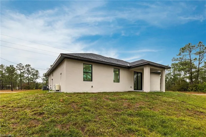 Back of house with cooling unit and a lawn