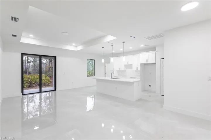 Unfurnished living room with sink and a raised ceiling