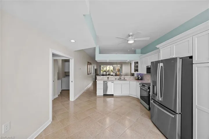 Kitchen featuring stainless steel appliances, white cabinets, a peninsula, light tile patterned flooring, and light countertops