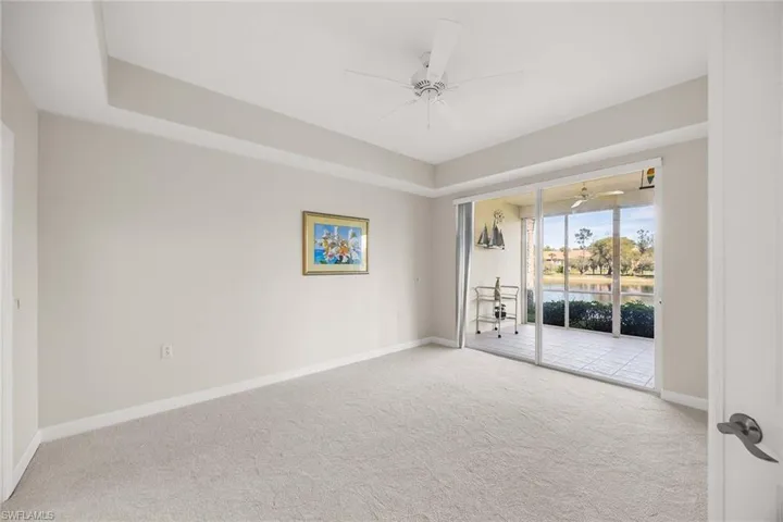 Unfurnished room with a ceiling fan, light colored carpet, and a water view