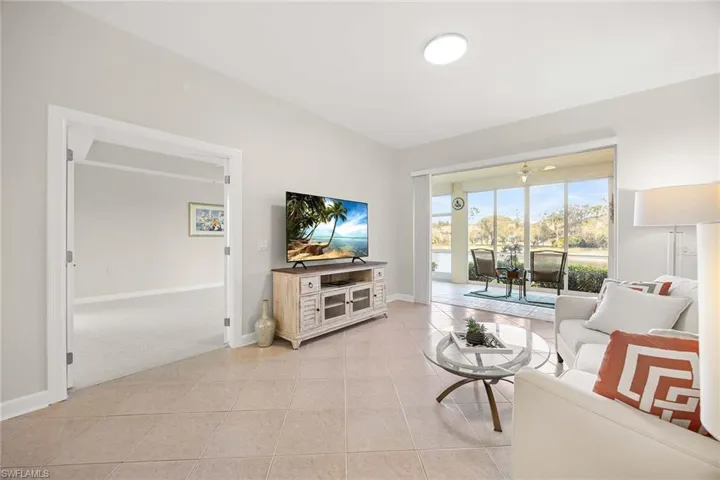 Living room with light tile patterned flooring and light colored carpet