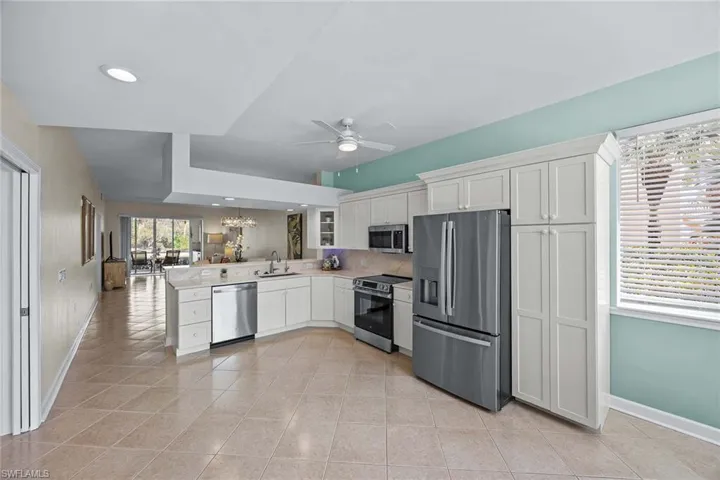 Kitchen featuring stainless steel appliances, light countertops, a peninsula, ceiling fan, and hanging lights