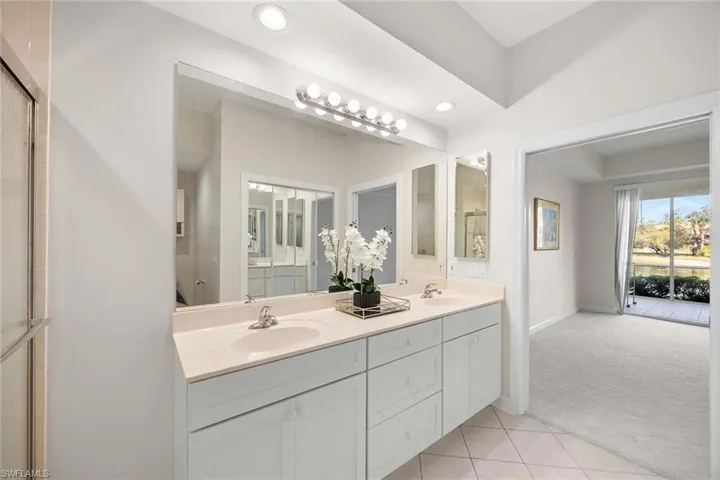 Bathroom with double vanity, light carpet, light tile patterned flooring, and recessed lighting