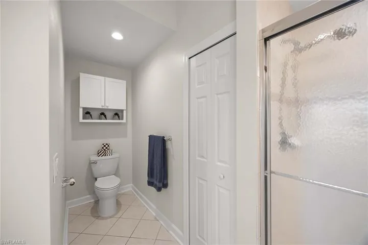 Bathroom featuring light tile patterned floors, a stall shower, a closet, and recessed lighting