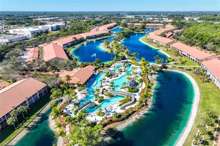 Drone / aerial view of a nearby body of water and apartment complex / building