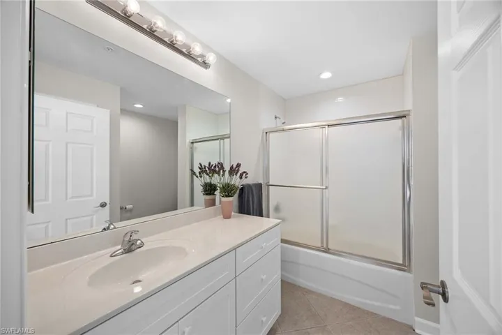 Bathroom with vanity, light tile patterned floors, combined bath / shower with glass door, and recessed lighting