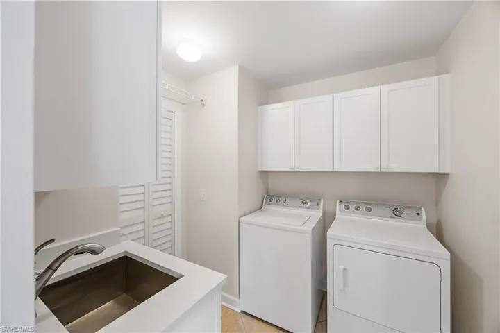 Laundry area with cabinet space, washing machine and dryer, and light tile patterned flooring