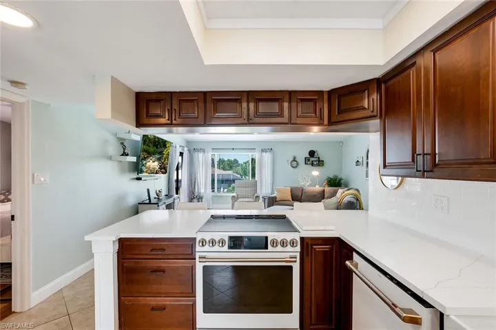 Kitchen featuring a peninsula, electric range, light countertops, open floor plan, and tasteful backsplash