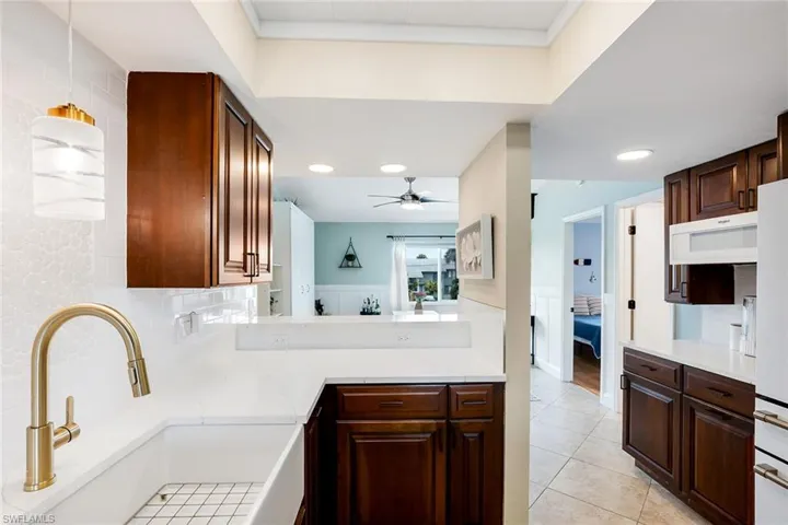 Kitchen with decorative backsplash, light tile patterned flooring, a ceiling fan, light stone countertops, and ornamental molding