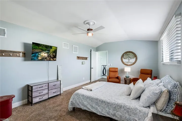 Bedroom with lofted ceiling, ceiling fan, and dark carpet
