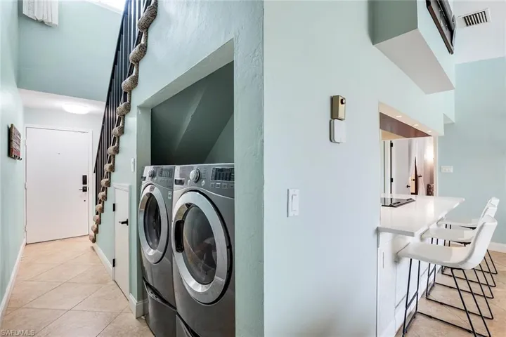 Laundry area featuring light tile patterned flooring and independent washer and dryer