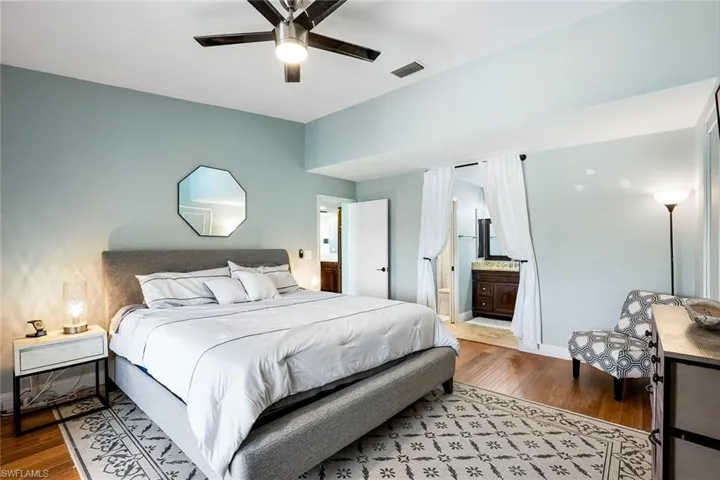 Bedroom featuring dark wood-type flooring, a ceiling fan, and ensuite bath