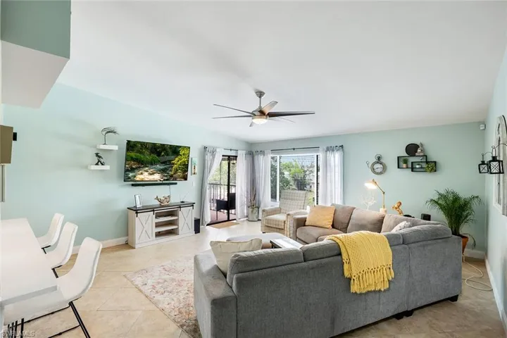 Living area featuring ceiling fan, vaulted ceiling, and light tile patterned flooring