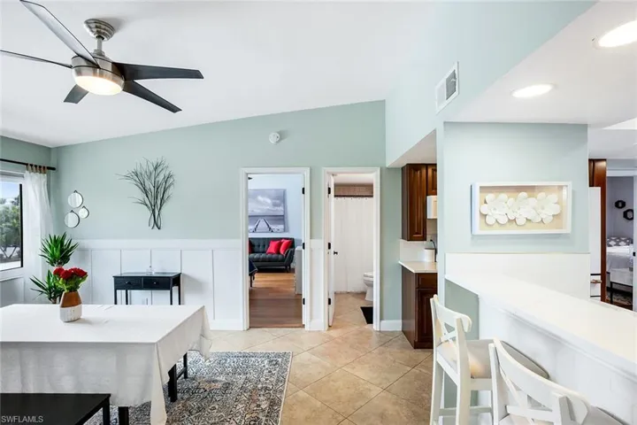 Dining room featuring a wainscoted wall, ceiling fan, and light tile patterned flooring