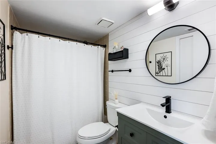 Full bathroom featuring vanity, a shower with curtain, and wooden walls