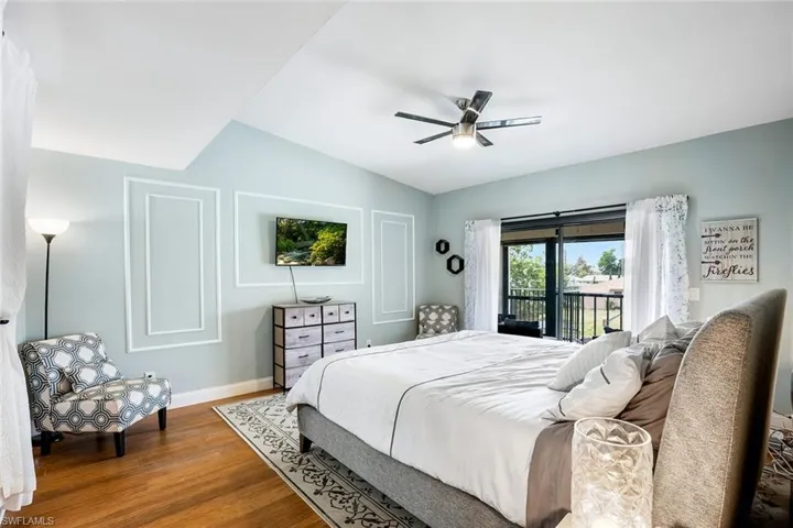 Bedroom with wood finished floors, access to outside, a ceiling fan, and lofted ceiling