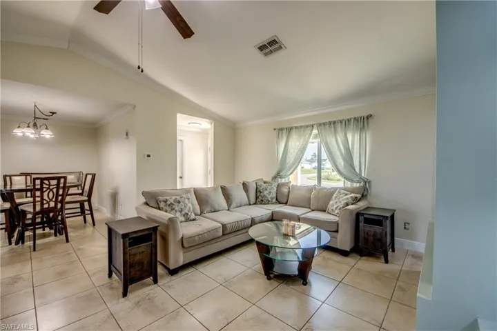 Great room with lofted ceiling, fan, dining room chandelier, and crown molding