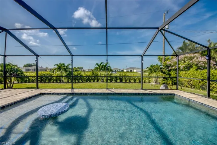 Gorgeous swimming pool with a built-in cocktail table and lush, tropical landscaping