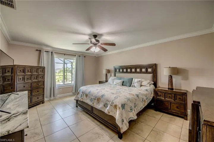 Primary bedroom featuring crown molding, picture window and ceiling fan