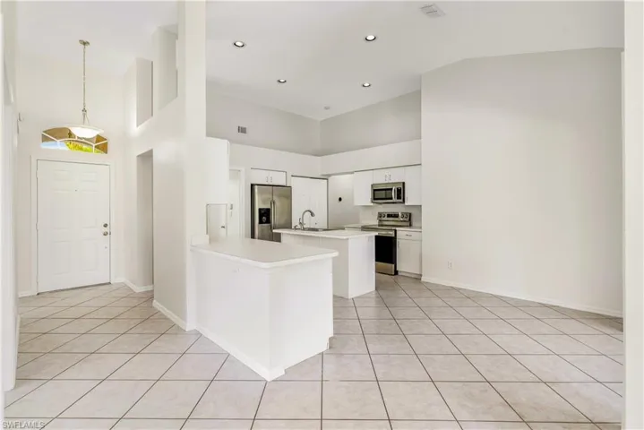 Open concept living space featuring a kitchen with white cabinetry, stainless steel appliances, and a central island.
