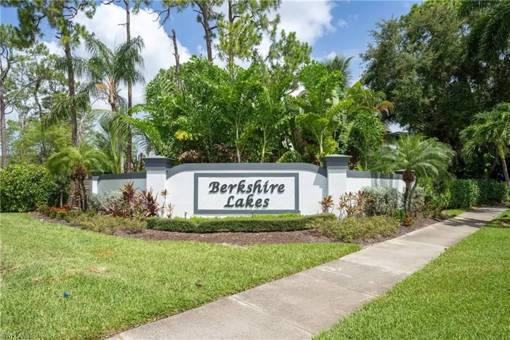 Berkshire Lakes community entrance sign featuring a white and gray stucco wall, integrated landscaping, mature palm trees, and established green foliage