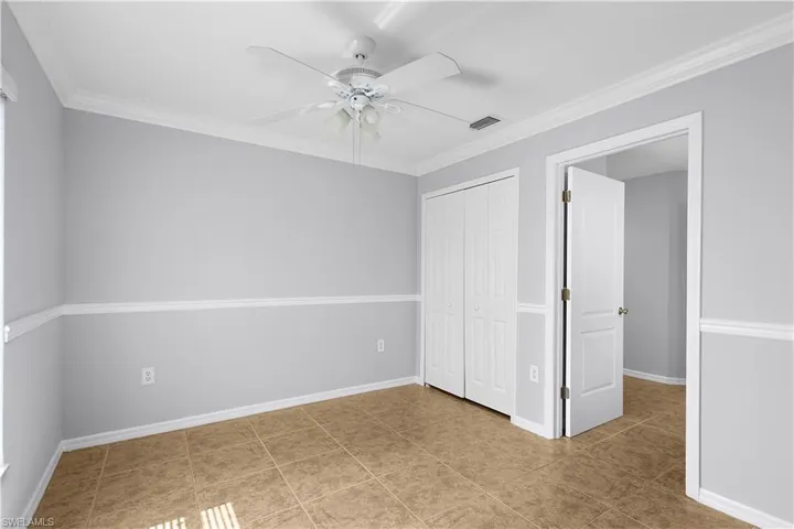 Spacious secondary bedroom featuring neutral paint tones, decorative chair rail molding, and wood-finish flooring