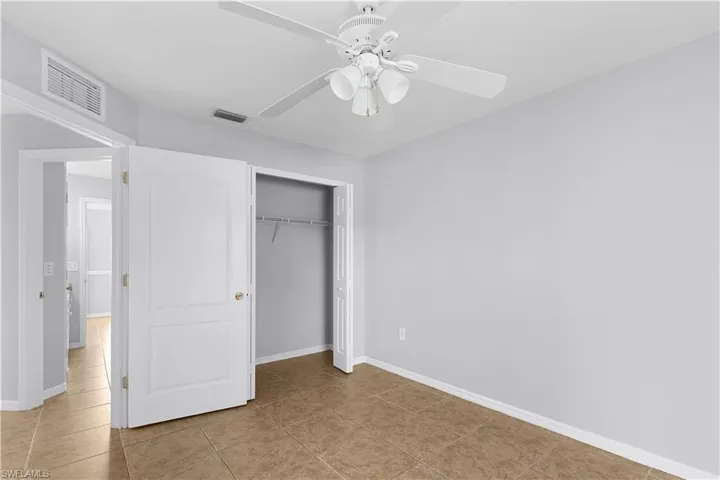 Tile flooring, ceiling fan with integrated lighting, bi-fold closet doors, and light gray wall paint