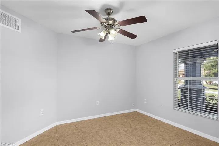 Bright corner bedroom with neutral wall finishes, wood-finish flooring, and abundant natural light from large windows