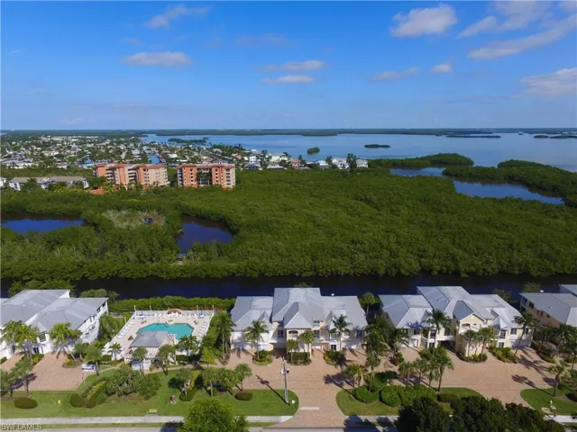 Aerial view of residential area featuring a nearby body of water and a pool