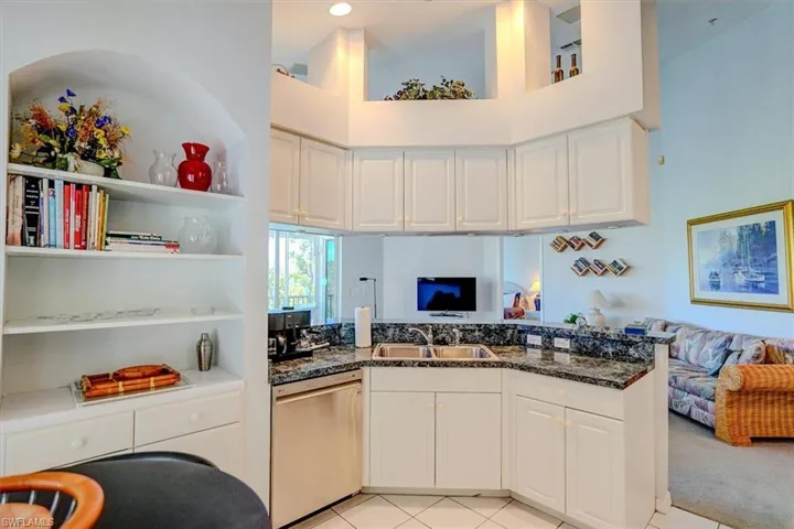 Kitchen with stainless steel dishwasher, open floor plan, a peninsula, a high ceiling, and white cabinets