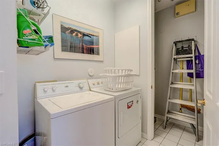 Laundry room with separate washer and dryer and light tile patterned floors
