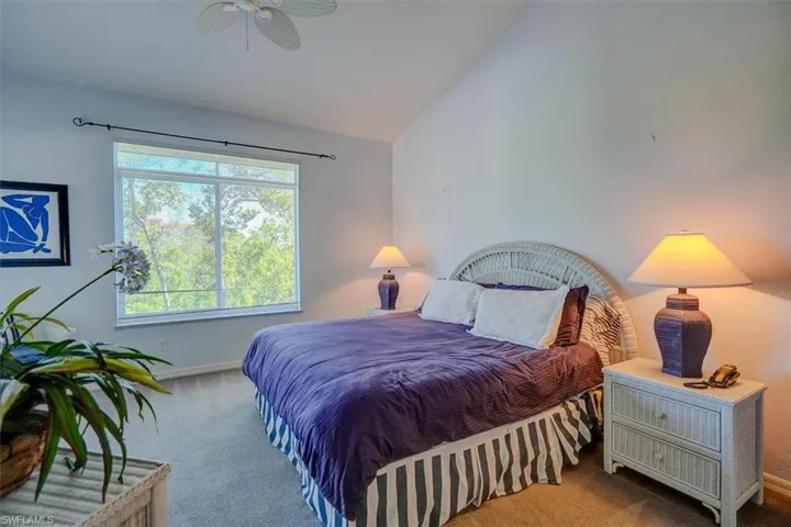 Carpeted bedroom with lofted ceiling and ceiling fan