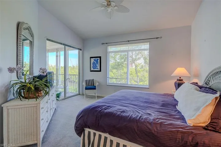 Carpeted bedroom featuring access to outside, vaulted ceiling, and ceiling fan