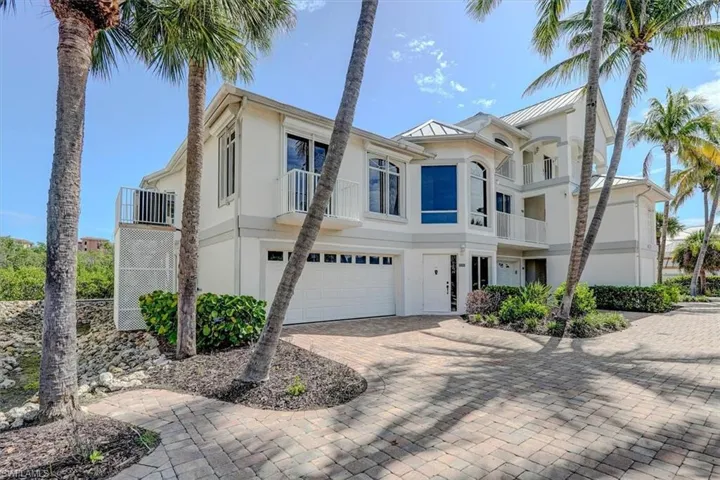 View of front of property featuring stucco siding, an attached garage, driveway, and a balcony