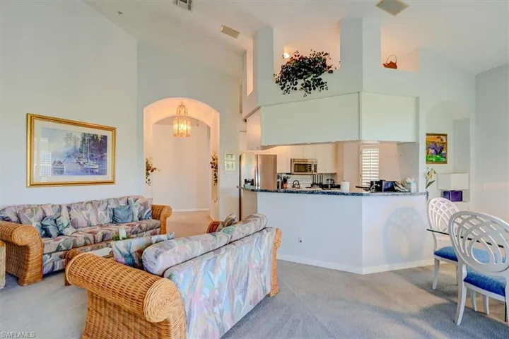 Living room featuring arched walkways, light carpet, and a high ceiling
