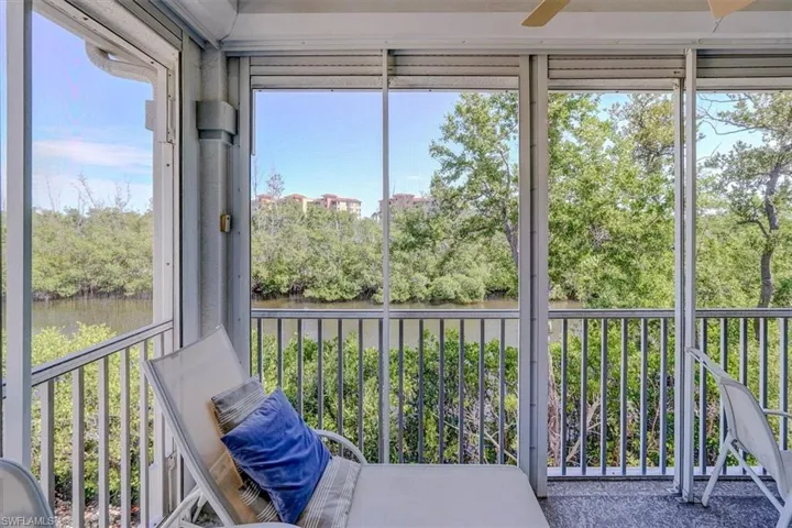 Sunroom / solarium featuring ceiling fan, a water view, healthy amount of natural light, and view of wooded area