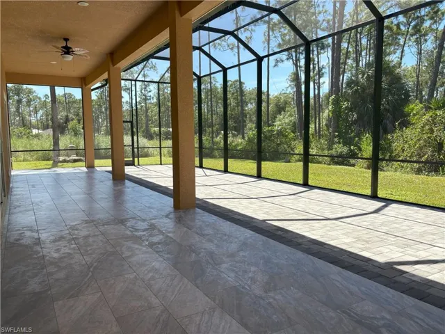 Unfurnished sunroom featuring a ceiling fan and a patio area