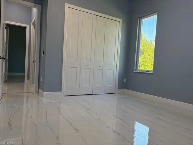Unfurnished bedroom with light marble finish floors and a closet