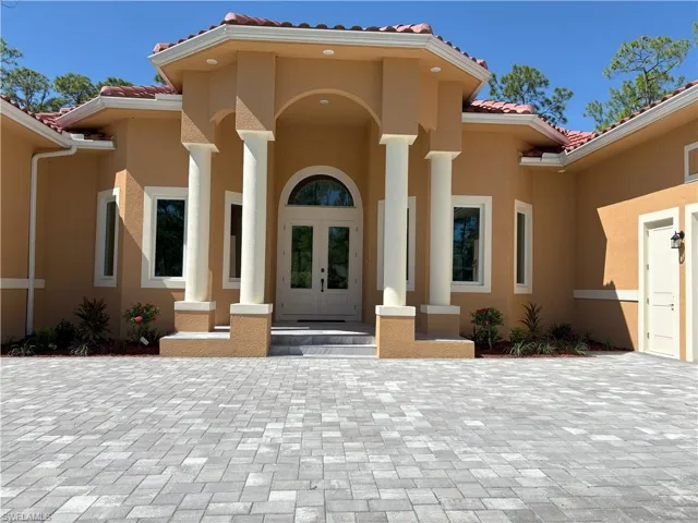 Entrance to property with a tiled roof, a porch, french doors, and stucco siding